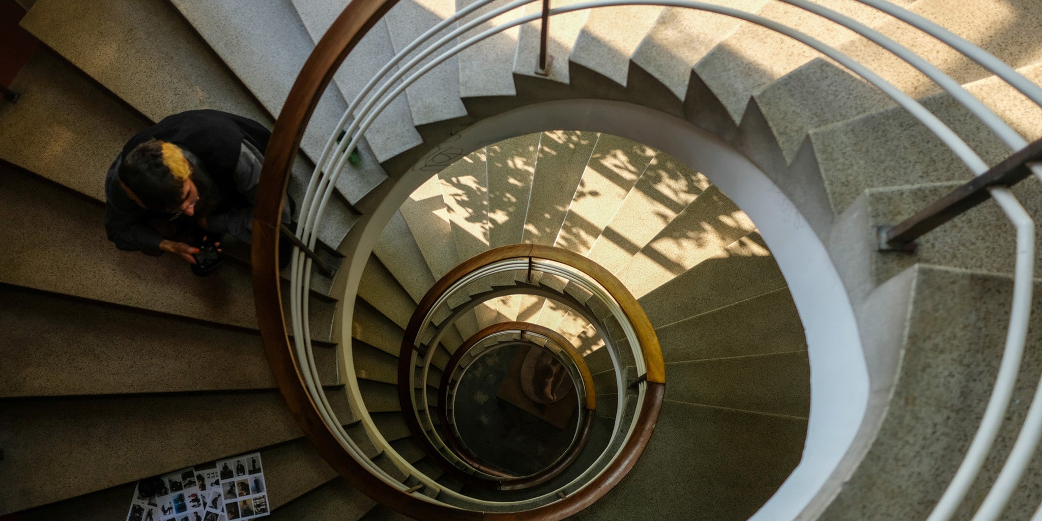Lines of Thought BTS: spiral stair from above with styling assistant, Joao; contact sheets on a step.